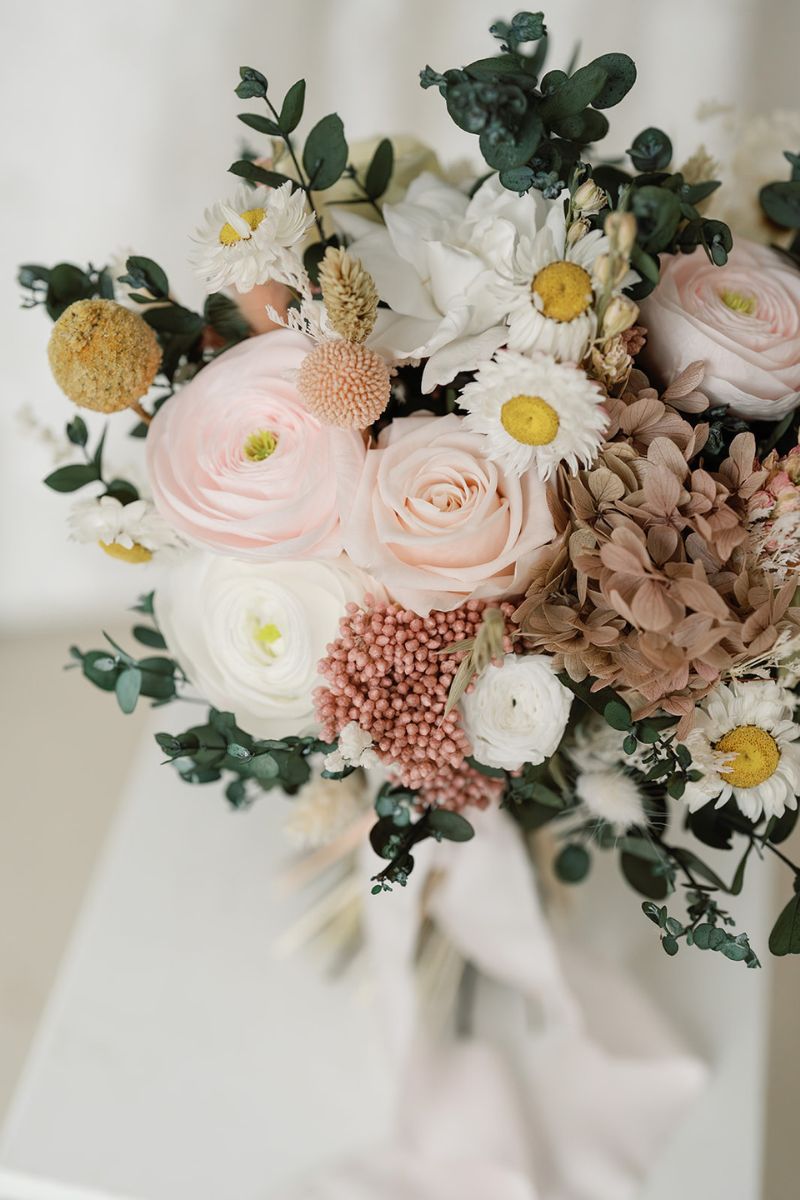 Close up of garden inspired dried and preserved bridal bouquet in lemon, pale pink, white and green