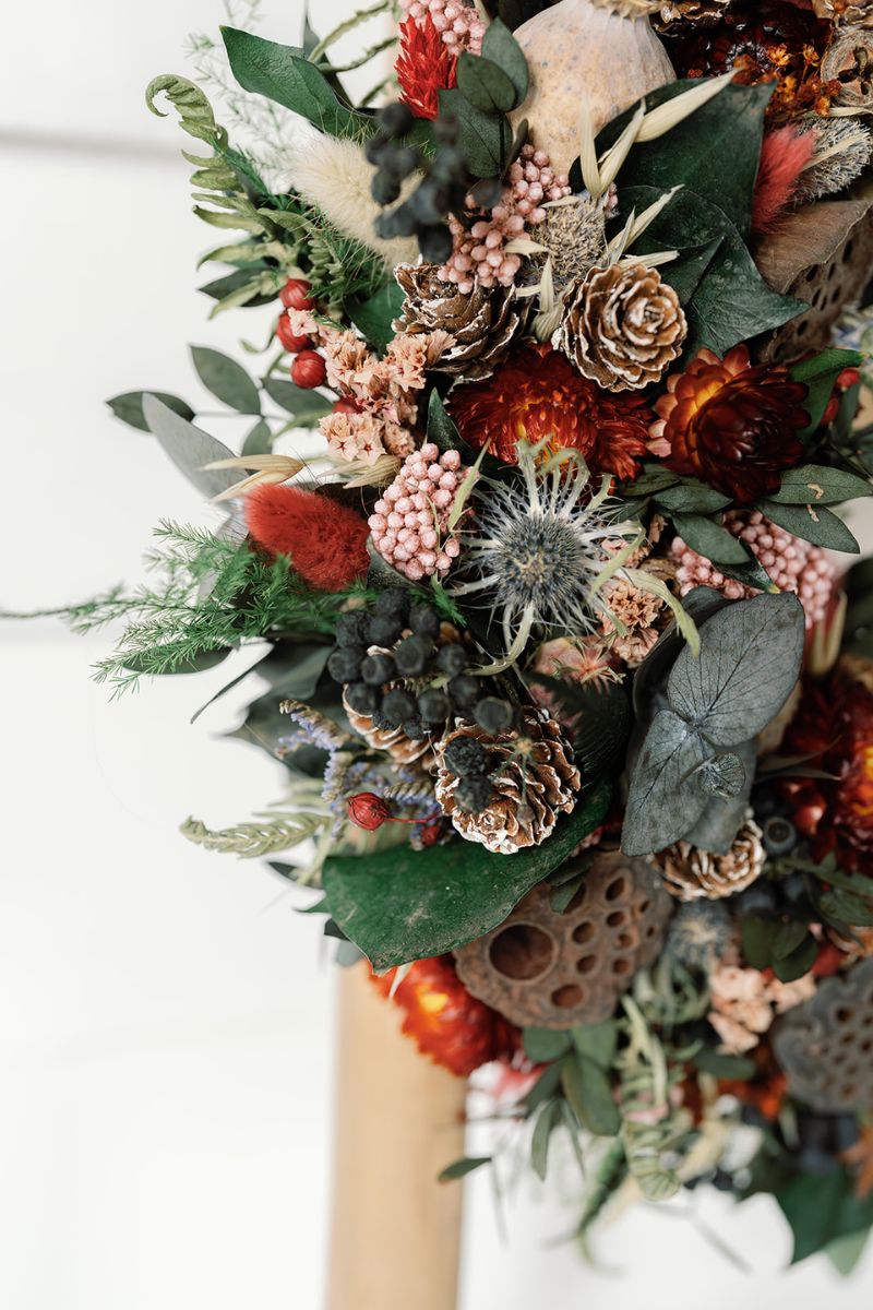 Decorative wreath with pinecones, berries, and other natural elements on a white background