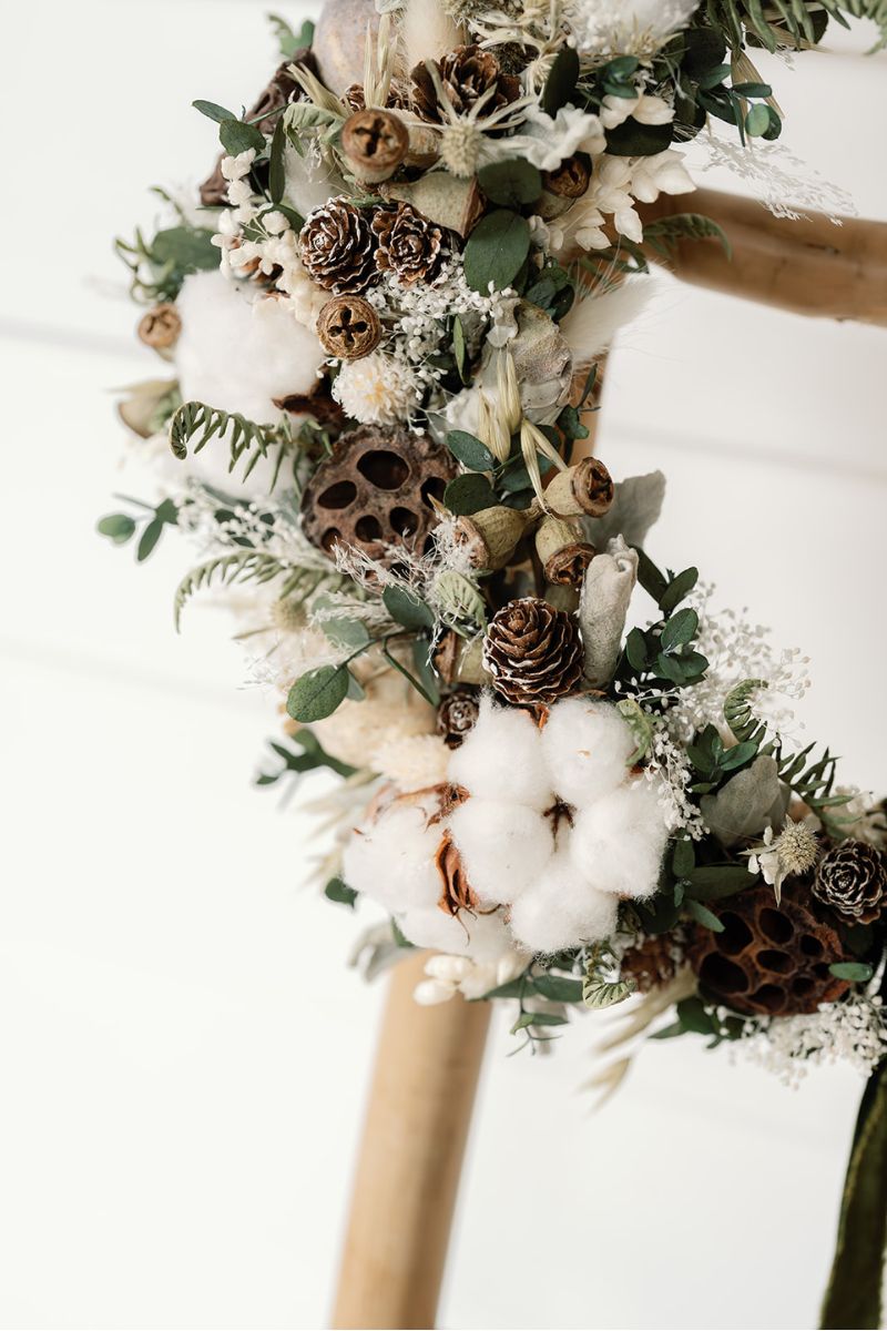 Festive dried flower wreath with cotton balls, pinecones, and greenery