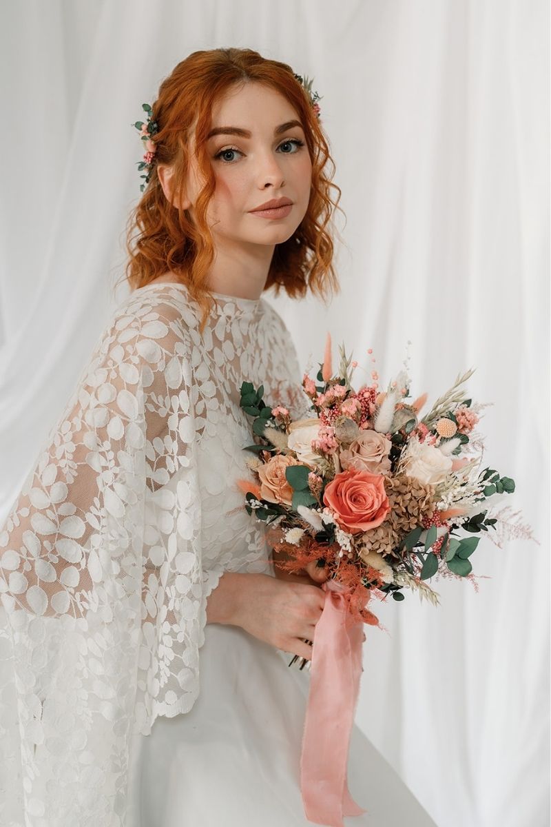 Wildflower style dried flower bridal bouquet featuring coral pink, white and nude flowers with lush greenery and fluffy ferns