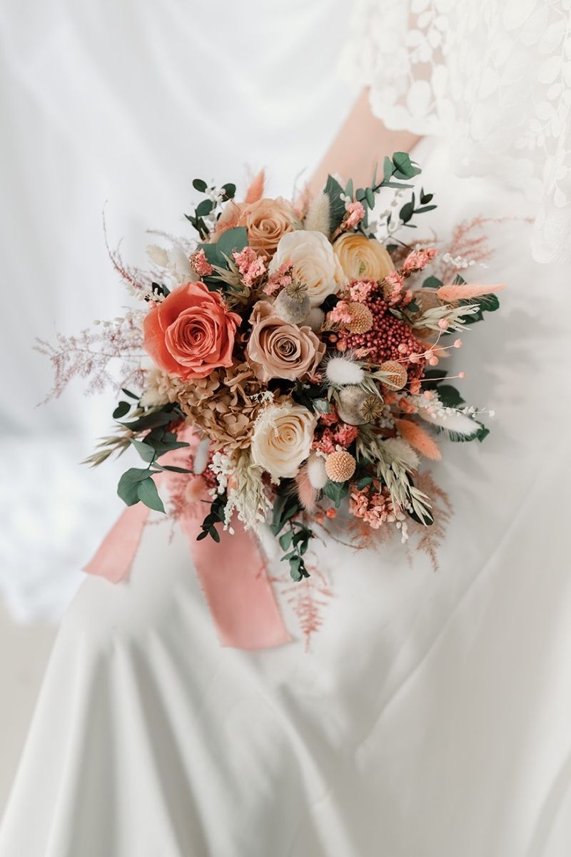 Wildflower style dried flower bridal bouquet featuring coral pink, white and nude flowers with lush greenery and fluffy ferns