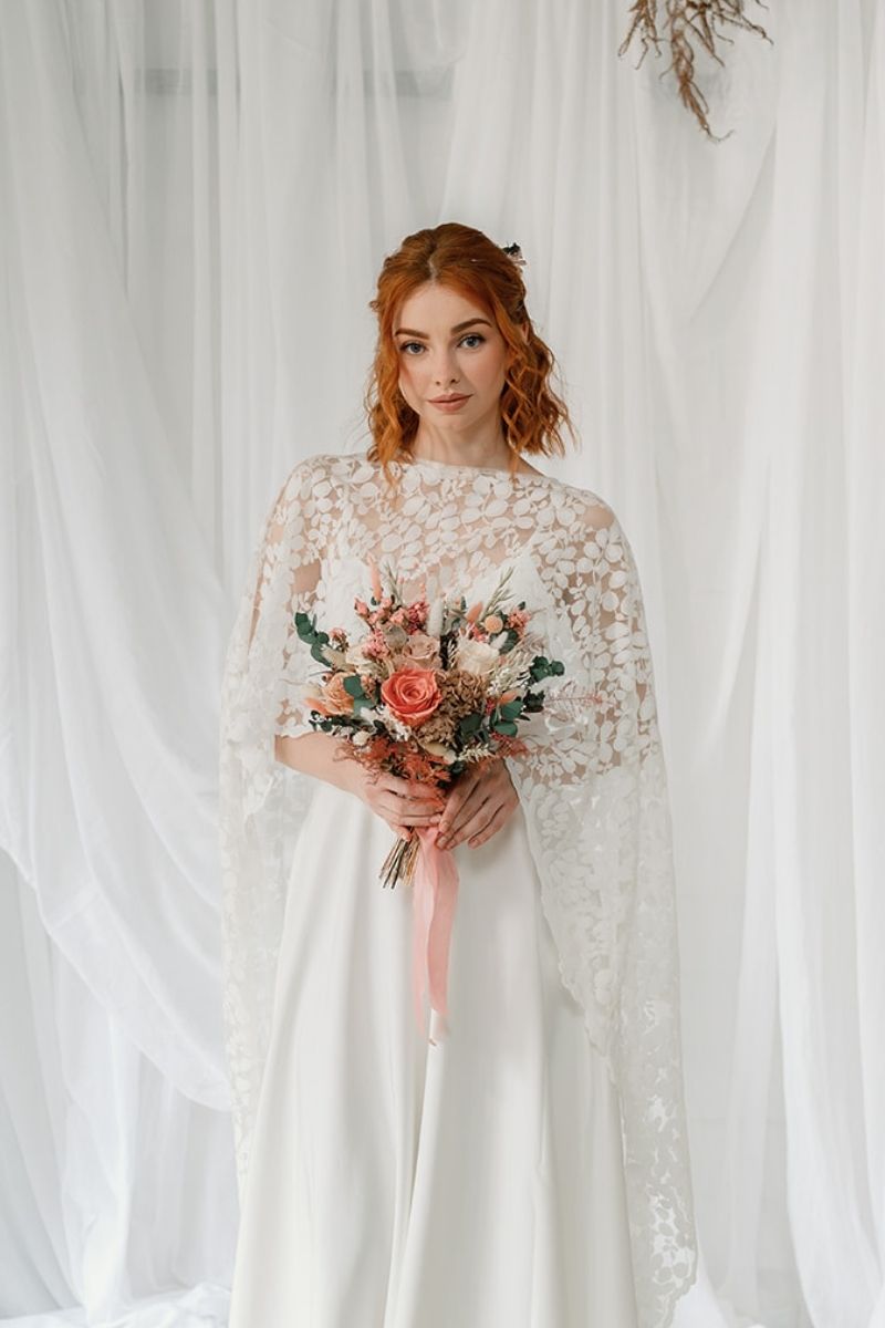 Wildflower style dried flower bridal bouquet featuring coral pink, white and nude flowers with lush greenery and fluffy ferns