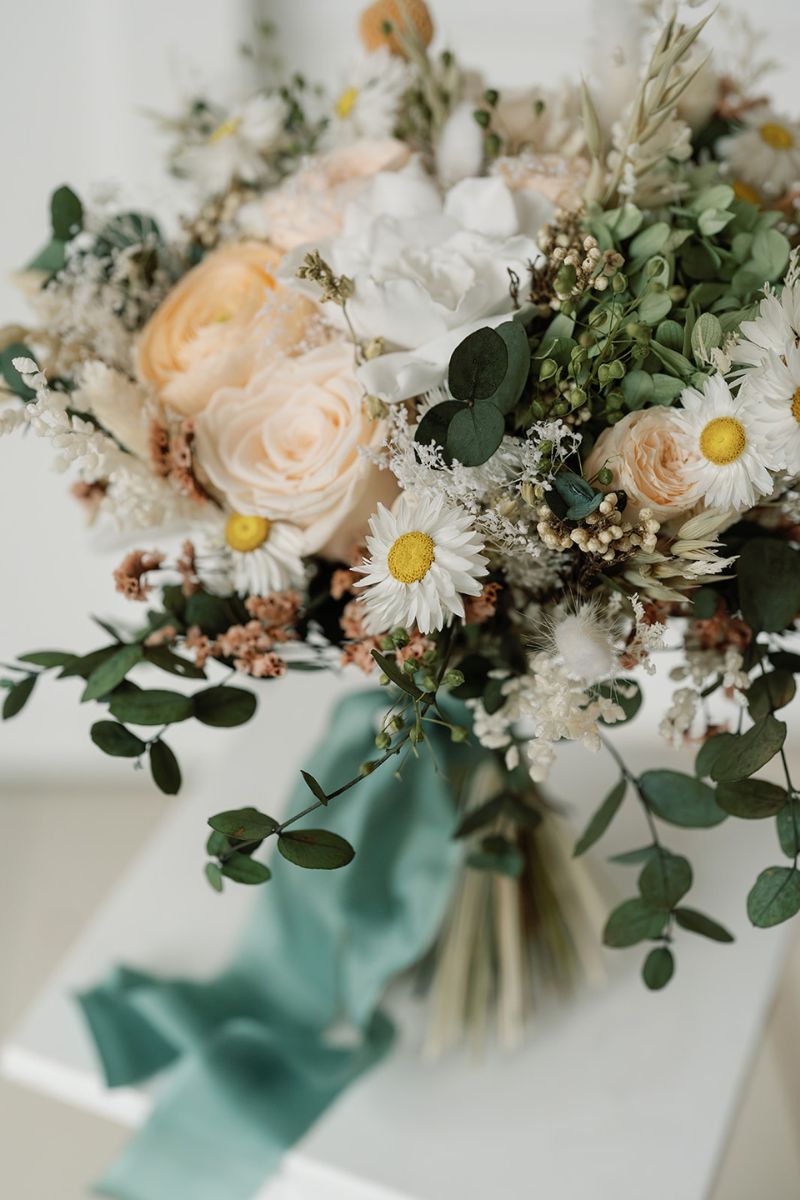 Close up of romantic wildflower bridal bouquet in peach, white and green with hand dyed silk ribbon  