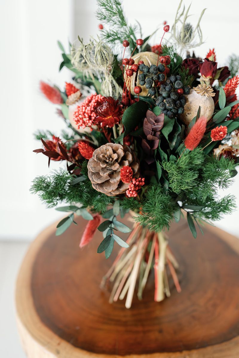 Festive bouquet of dried flowers with pinecones and berries.