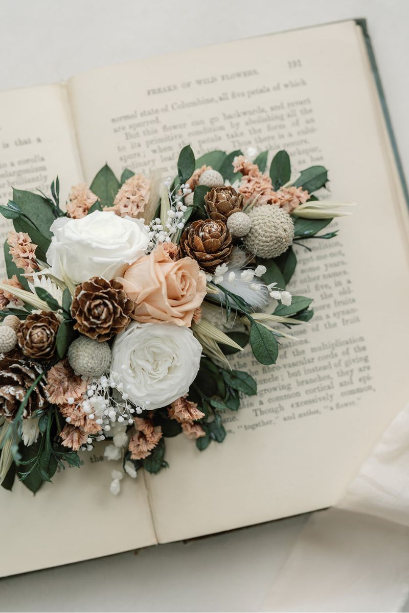 Close up of the Clara hair clip, inspired by frosty mornings, this winter whites wedding dried flower hair clip features preserved roses in nude and white, surrounded by lush foliage and silver berries.
