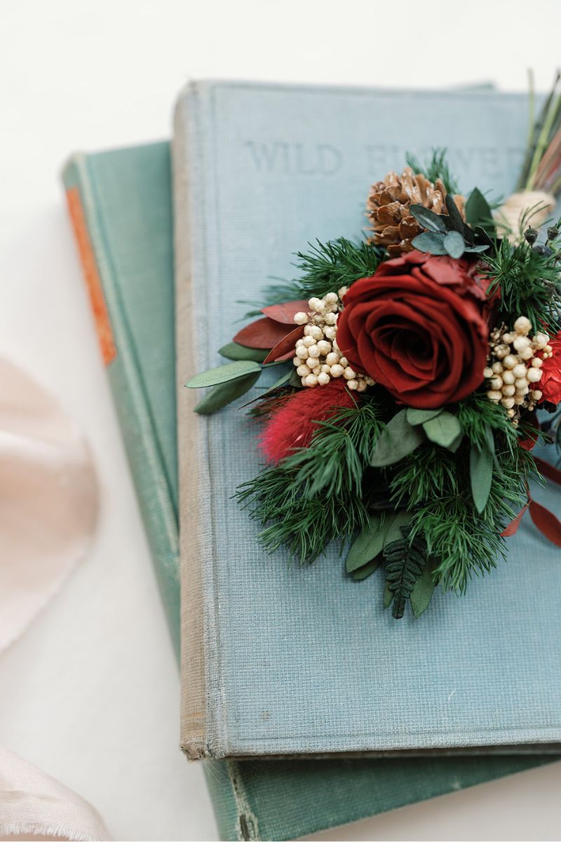 Close up of the Ebony dried and preserved winter wedding grooms buttonhole with preserved red rose and lush green ferns, a traditional colour scheme with a fresh bohemian twist by Luna and Wild.