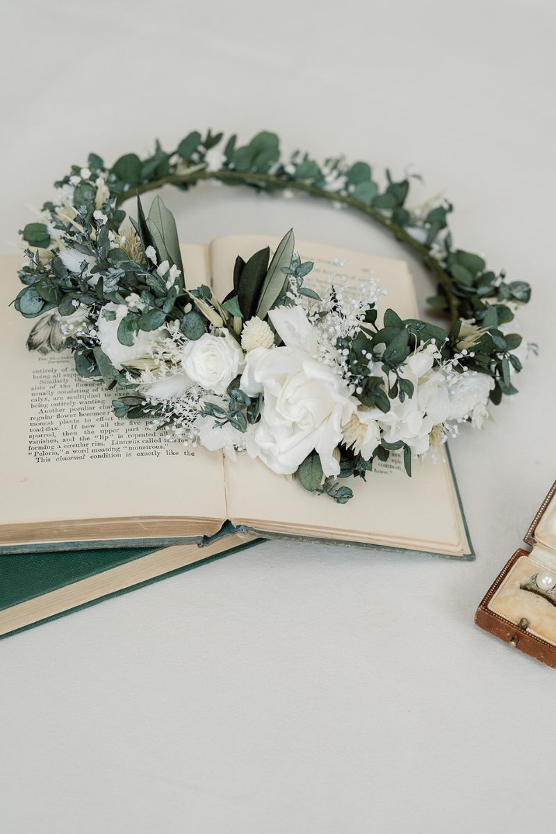 green and white full circular dried flower crown with a focal arrangement of white roses and hydrangea.