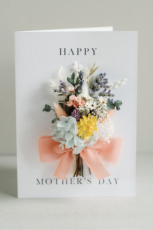 Mini dried flower gift bunch in pastel tones tied onto a happy mothers day card, tied with ribbon.