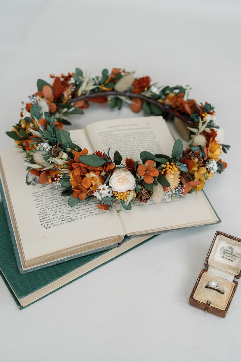 Autumnal dried flower crown with mini peach preserved roses, pine cones, daisies, straw flowers and eucalyptus, a full circular crown.