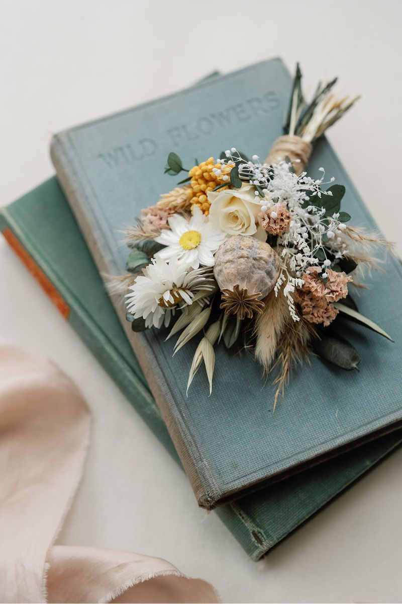 Rustic, boho style dried flower buttonhole in a palette of mustard yellow, champagne, sage, white and soft browns, finished with twine wrapped half way down the stems.