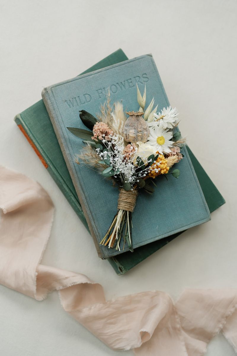 Rustic, boho style dried flower buttonhole in a palette of mustard yellow, champagne, sage, white and soft browns, finished with twine wrapped half way down the stems.