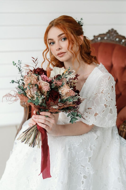 Contemporary modern bohemian bridal bouquet in colour scheme of red wine and dusky pink mixed with lush green preserved foliage, finished with a red wine silk ribbon.