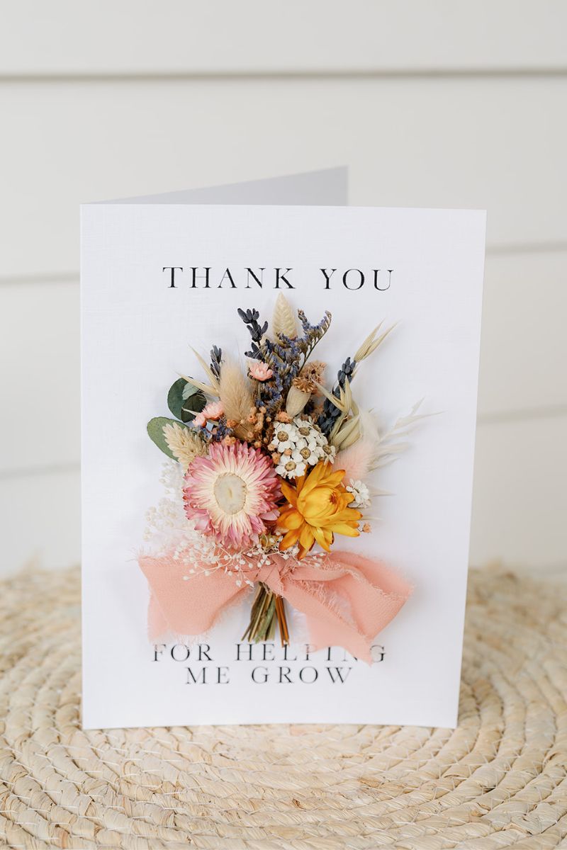 a colourful mini dried flower bunch bouquet hand tied onto a white card which reads "thank you for helping me grow"